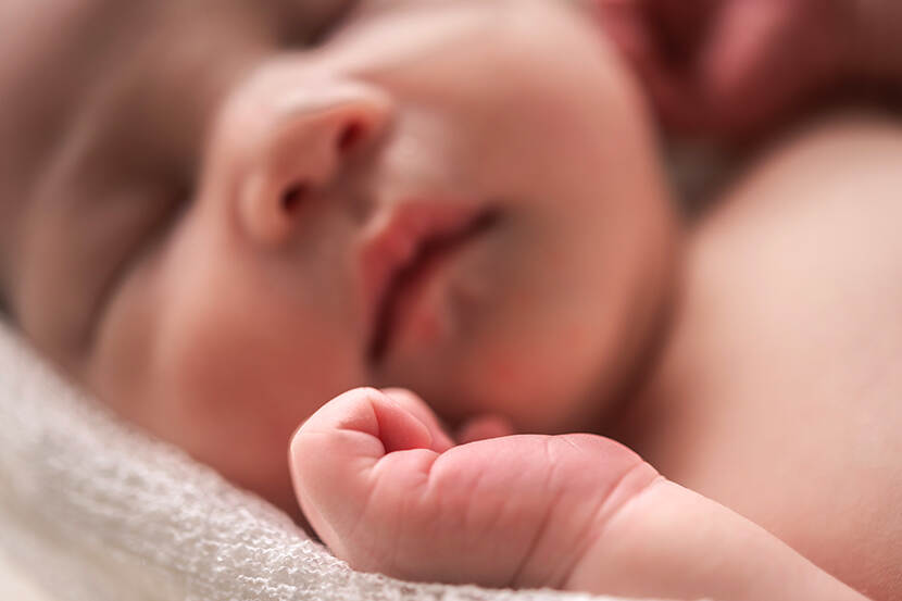 Baby met handje op de voorgrond.