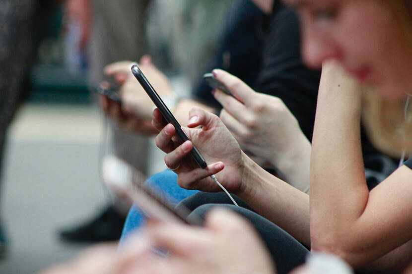 Handen op een rij bezig met hun smartphone.